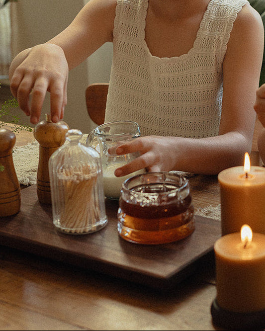 Woman and two children at a table with tea and candles, enjoying a warm, homey atmosphere.